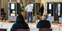 Voters cast ballots as election workers look on